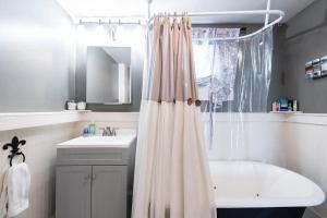bagno con tenda per la doccia, vasca e lavandino di Spacious Historic House Near Louisville Sites a Louisville