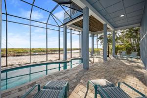 a room with a pool and chairs and windows at Papa's Boat House - 8214 Estero Blvd home in Fort Myers Beach