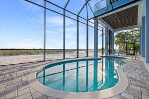 an indoor swimming pool in a house with glass walls at Papa's Boat House - 8214 Estero Blvd home in Fort Myers Beach