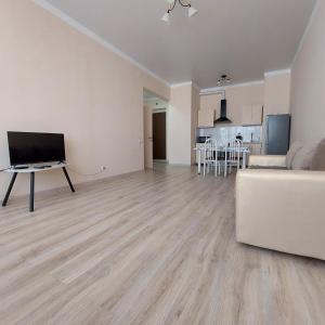 an empty living room with a couch and a kitchen at Жк Metropole 2х комнатная in Almaty