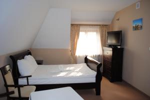 1 dormitorio con 1 cama, TV y ventana en Pensjonat Bobrowy Dwór, en Szelków Stary