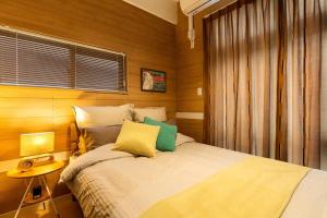a bedroom with a bed and a table and a window at 車いらずの好立地! 小さいながらも機能的なナチュラルコンパクトルーム Reveur Tsuji in Naha