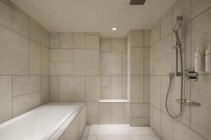 a bathroom with a shower and a bath tub at Courtyard by Marriott Tokyo Ginza Hotel in Tokyo