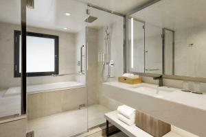 ein Bad mit einer Dusche, einem Waschbecken und einem Spiegel in der Unterkunft Courtyard by Marriott Tokyo Ginza Hotel in Tokio
