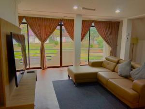 een woonkamer met een bank en grote ramen bij LiLLA Hilltop Retreats Janda Baik formerly known as Serene Resort in Bentong