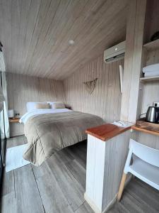1 dormitorio con 1 cama y suelo de madera en Mini Cabaña con Tinaja en Máfil