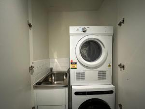 een wasmachine in een kamer met een wastafel bij Generous 2br2ba Docklands Free Parkingpool in Melbourne