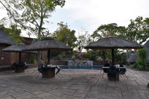 a patio with tables and umbrellas and a pool at Tipperary Game Lodge - Mbombela in Karino