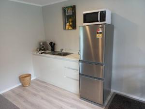 a kitchen with a stainless steel refrigerator with a microwave at Cute, new two bedroom cottage with shared pool in Cambridge