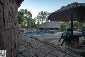 a chair and an umbrella next to a swimming pool at Tipperary Game Lodge - Mbombela in Karino