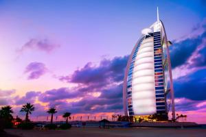 een hotelgebouw aan het strand met een zonsondergang bij Business Bay Apt with Rooftop Pool, Fast WiFi, and near Burj Khalifa in Dubai