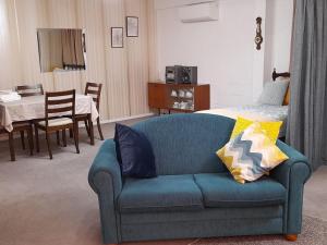 ein Wohnzimmer mit einem blauen Sofa und ein Schlafzimmer in der Unterkunft Park View 'Home Away From Home' in Feilding