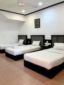 3 łóżka w pokoju z białymi ścianami w obiekcie Intan Beach Resort w mieście Kuala Terengganu