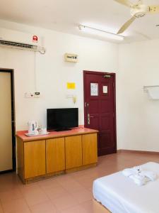 a room with a desk with a television and a door at Intan Beach Resort in Kuala Terengganu