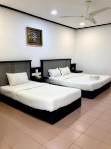 two beds in a room with white walls at Intan Beach Resort in Kuala Terengganu