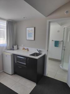 a small kitchen with a sink and a shower at Southpacific Motel in Whangamata