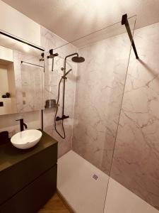 een badkamer met een wastafel en een glazen douche bij Studio Duinenzicht in Koksijde