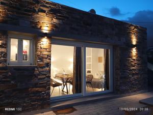 a sliding glass door on a stone house with a dining room at Sea melody tinos 3 in Agios Sostis