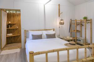 a bedroom with a bed with white sheets and a shelf at Orion Healing Centre in Srithanu