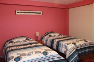 Cusco Apartment في كوسكو: سريرين في غرفة بجدران حمراء