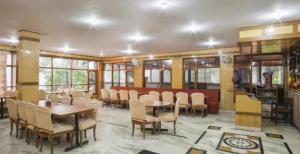 a dining room with tables and chairs and windows at Hotel Dalhousie Shangrila Hotel Near Hill Station - Natural Landscape & Mountain View - Comfortable Stay with Family in Dalhousie
