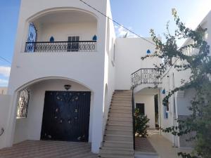 een trap naar een zwarte deur in een wit gebouw bij Villa Chaâbane in Djerba