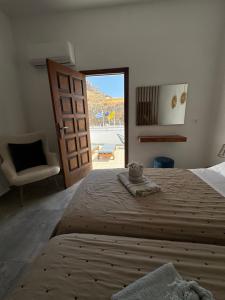 a bedroom with a bed and a chair and a door at Fedra Apartments Lindos in Líndos