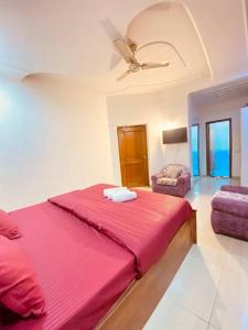 a bedroom with a red bed and a ceiling fan at Luxury duplex bungalow noida 50 in Noida