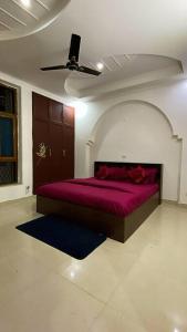 a bedroom with a purple bed with a ceiling fan at Luxury duplex bungalow noida 50 in Noida