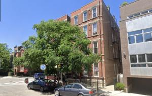a tree in front of a building with cars parked next to it at The Secret West Loop Oasis in Chicago