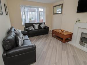 a living room with a black leather couch and a table at Sunshine Cottage in Morpeth