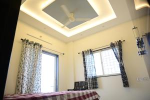 um tecto em caixote com uma ventoinha de tecto e janelas em Gurumauli Guesthouse em Akalkot
