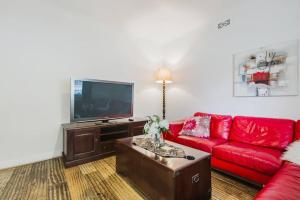 Il comprend un salon doté d'un canapé rouge et d'une télévision à écran plat. dans l'établissement Yarraville Garden Large home with yard and parking, à Yarraville
