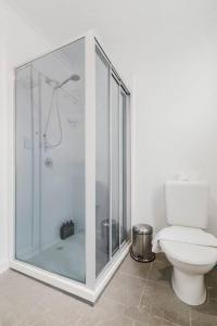 une salle de bain avec une douche en verre et des toilettes dans l'établissement Yarraville Garden Large home with yard and parking, à Yarraville