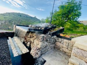 Hotel Hobbiton في T'mogvi: جدار عازل حجري مع نافورة مياه