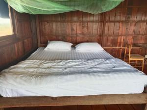 a bed in a room with a wooden wall at Banlung Hill Top House &Trekking in Phumĭ Pôy