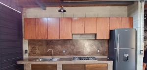 a kitchen with wooden cabinets and a stainless steel refrigerator at Casa Tapanco Tepoztlán in Tepoztlán