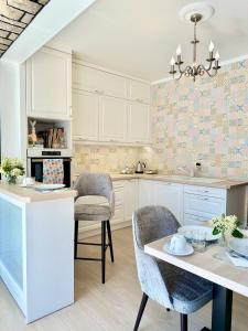 - une cuisine avec des placards blancs, une table et des chaises dans l'établissement Éllő Residence, à Veszprém