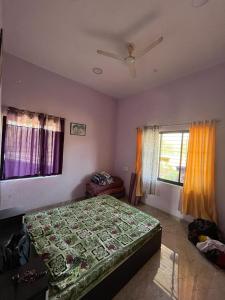 a bedroom with a bed with a green comforter and two windows at Raje Bhosale Farm in Ghātgarh