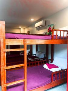 a room with three bunk beds with purple sheets at Bamboo Bungalow in Kampot
