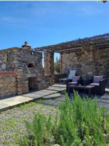 ein Steingebäude mit einer Terrasse mit 2 Stühlen und einem Tisch in der Unterkunft Le MONTE-CINTO -LOCATION EN PIERRE ENTRE MER ET MONTAGNE in Moltifao