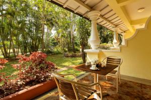 un porche con mesa, sillas y árboles en Fortune Resort Benaulim, Goa - Member ITC's Hotel Group, en Benaulim