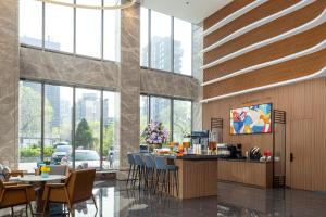 a lobby with a bar and chairs and windows at UrCove by Hyatt Tianjin West Railway STN in Tianjin