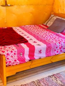 uma cama de madeira com uma colcha rosa e branca em New Mabroka em Nuweiba
