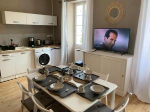 a kitchen with a table and a tv on the wall at Appartement charmant et cosy in Saint-Estèphe