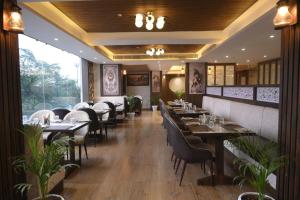 un restaurante con mesas y sillas y una gran ventana en Hotel The Plateau, en Ranchi