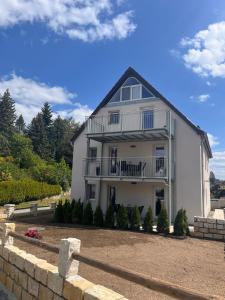 a large white house with a porch and balcony at Ferienwohnung Papststeinblick in Kurort Gohrisch