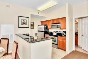 cocina con armarios de madera y encimera en 2BR Resort Suite - Fountain View Private Balcony, en Kissimmee