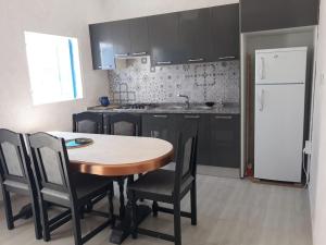 a kitchen with a table and chairs and a white refrigerator at Villa Yahia Djerba in Bou Menjel