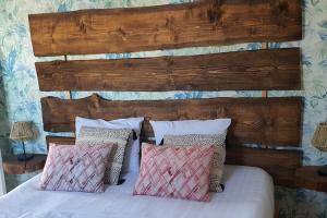 Bett mit einem Kopfteil aus Holz und Kissen in der Unterkunft Villa Yahia Djerba in Bou Menjel